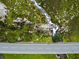 An aerial shot of a snowdonia road, mountain and waterfall.