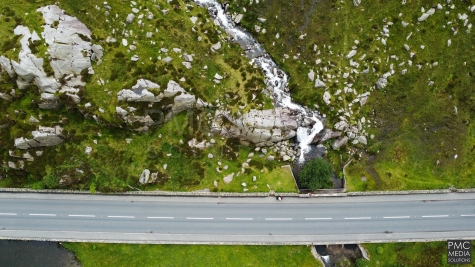 An aerial shot of a snowdonia road, mountain and waterfall.