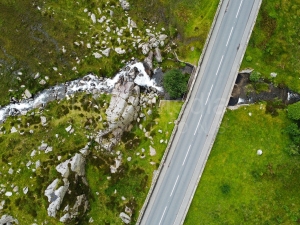 An aerial shot of a snowdonia road, mountain and waterfall.