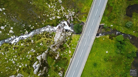 An aerial shot of a snowdonia road, mountain and waterfall.