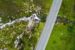 An aerial shot of a snowdonia road, mountain and waterfall.